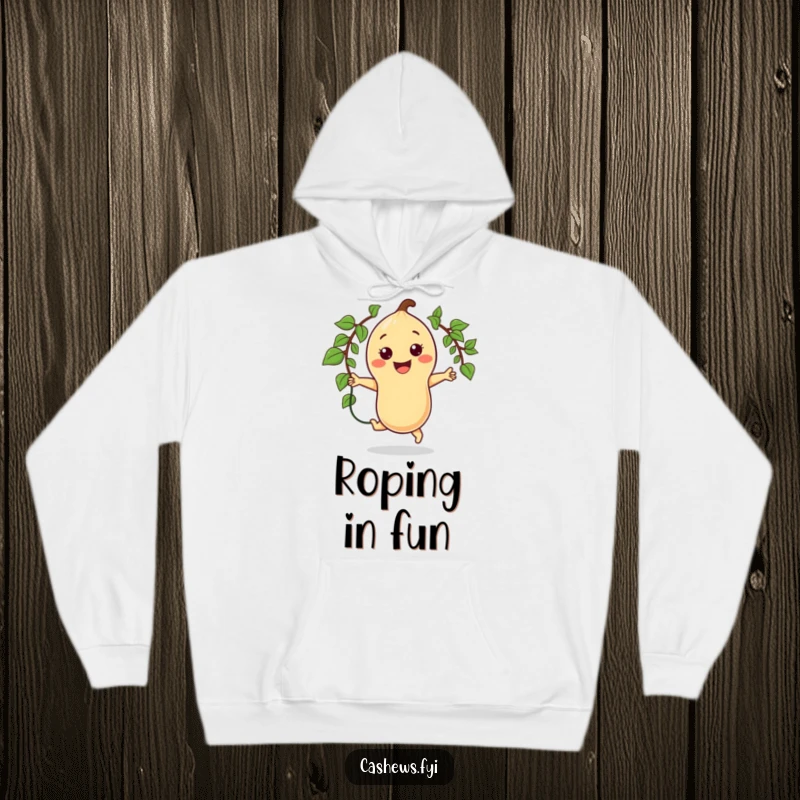 Funny hoodie depicting a kawaii cashew character enthusiastically jumping rope with a vine, a huge smile on its face, promoting active fun.