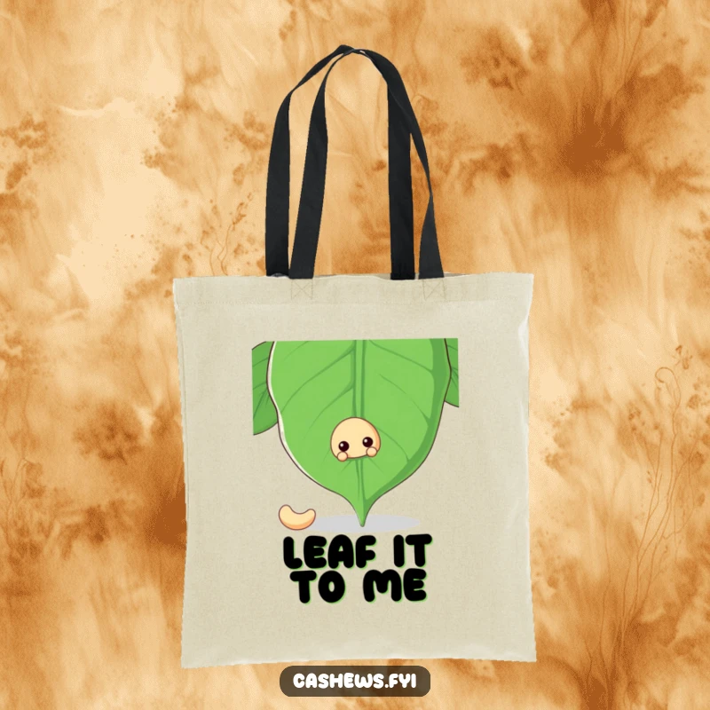 Funny tote bag with a cashew nut peeking from behind a giant cashew leaf, perfect for carrying items with a hint of mystery.